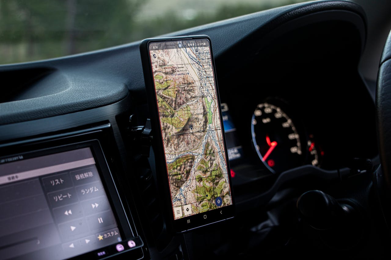 Close-up of a car dashboard with a smartphone holder displaying a map in Mongolia.